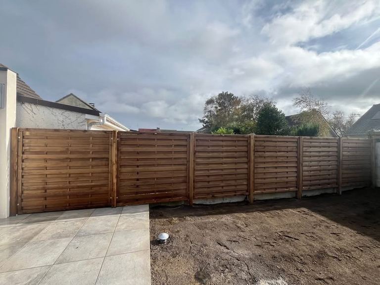 Après : Un jardin envahi, nettoyé, clôturé, prêt pour le gazon.